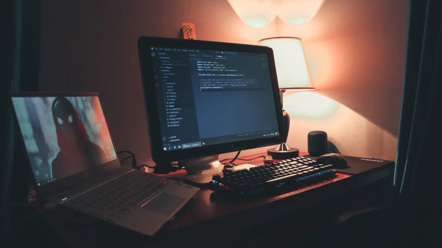 Game developer working on code with two monitors in a dark room